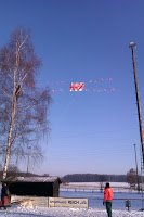 Ein Kletterer bringt in luftiger Höhe das Banner "11 Meter" an